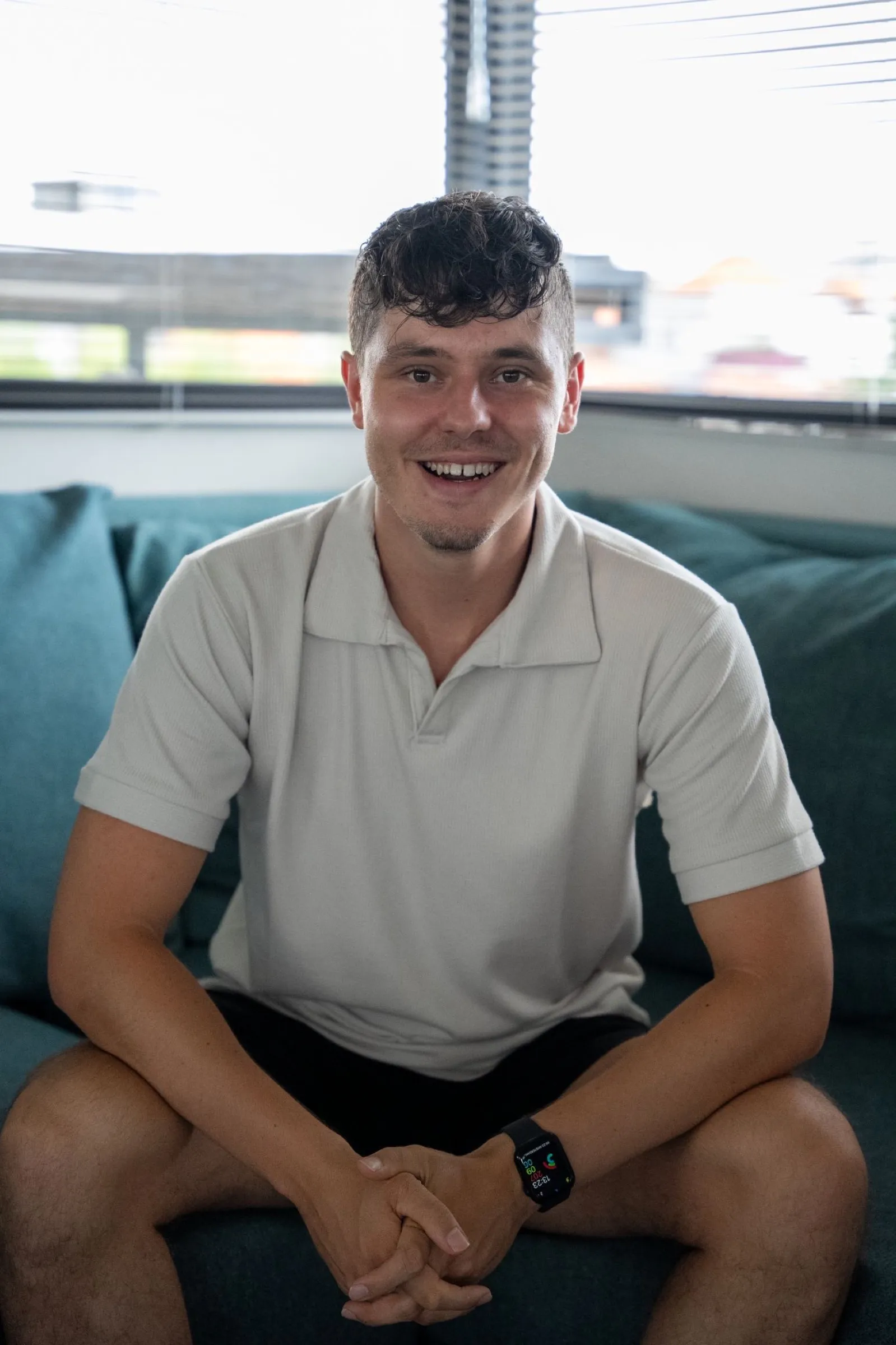 Hidde Berg sitting on a teal sofa, smiling
